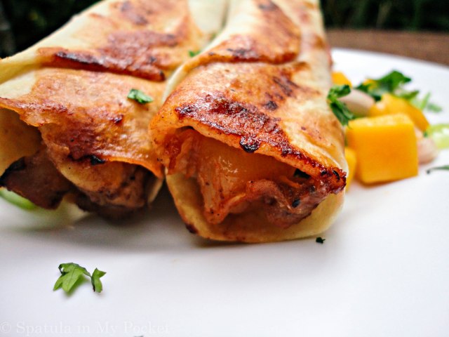 Hawaiian BBQ Taquitos. Filled with pineapples and mangoes, paired with a spicy tangy BBQ chicken, caramelized onions, and loads of fresh cheddar cheese.